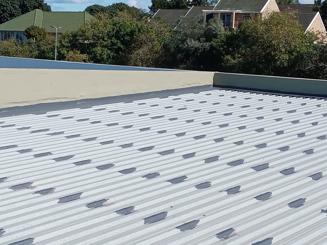 Corrugated roof with screw points and weak spots sealed before final coating