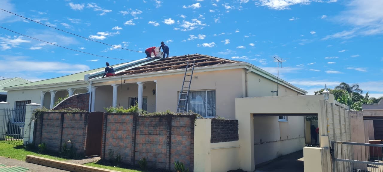 Re-roofing work in progress with roof sheets removed and contractors working on the roof